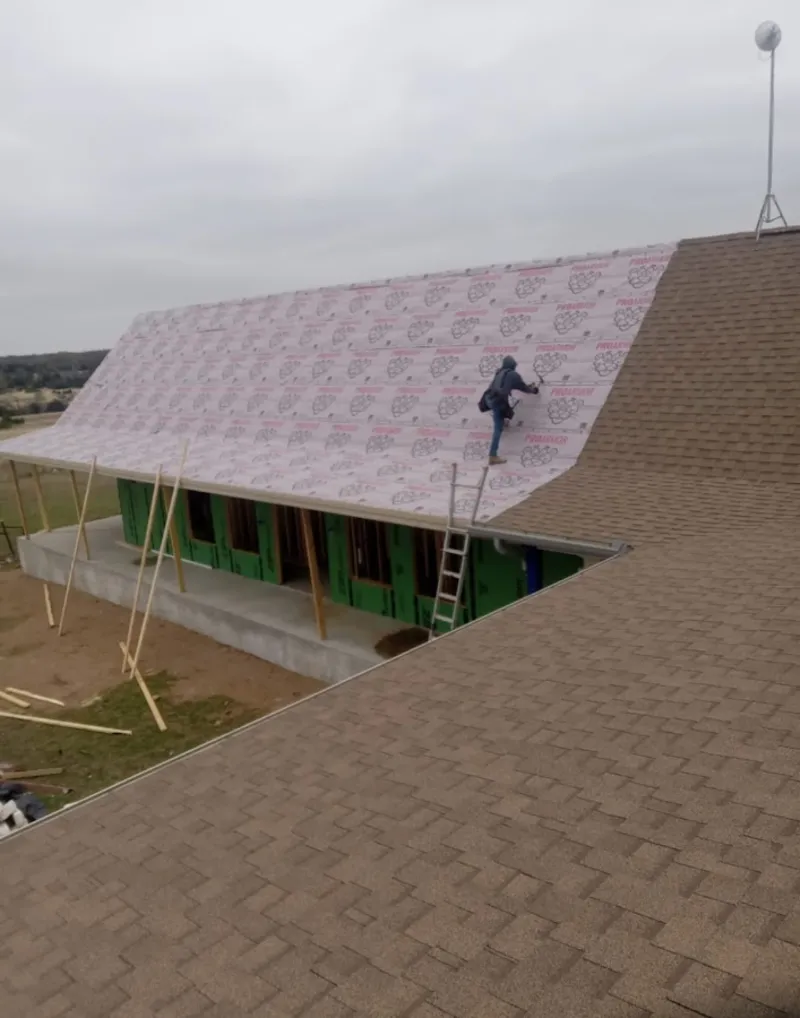 Worker preparing underlayment for a metal roof installation in Columbia Falls